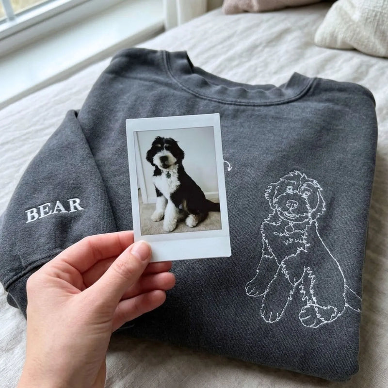 Close-up of personalized embroidery featuring a dog's face and name on a high-quality sweatshirt.