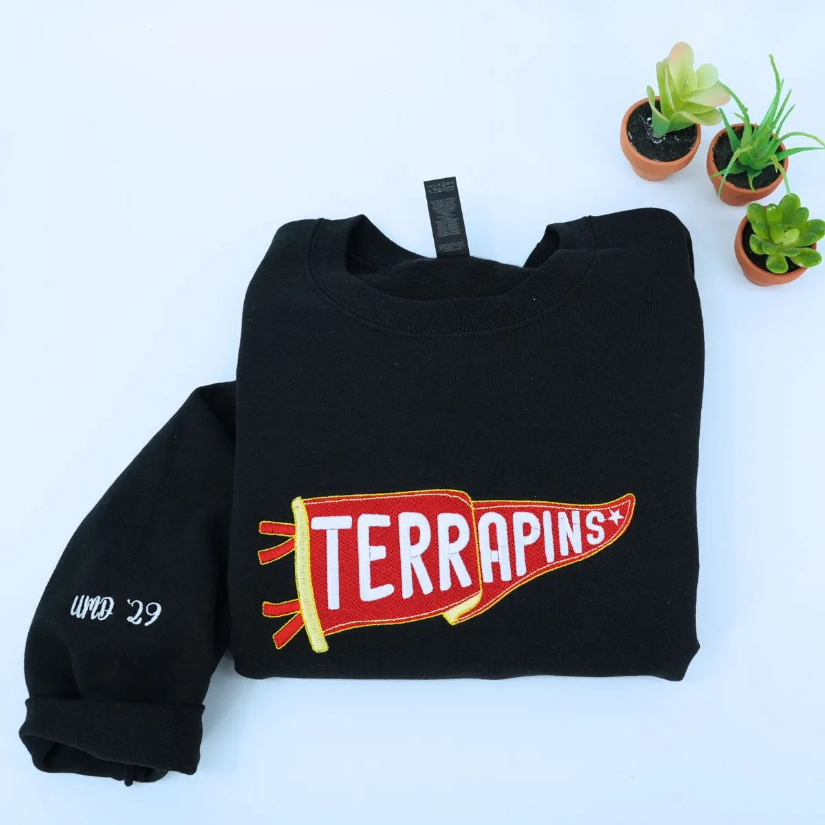 Custom embroidered Black pennant sweatshirt folded on table – personalized team name sweatshirt for school spirit, game day, and sports fans