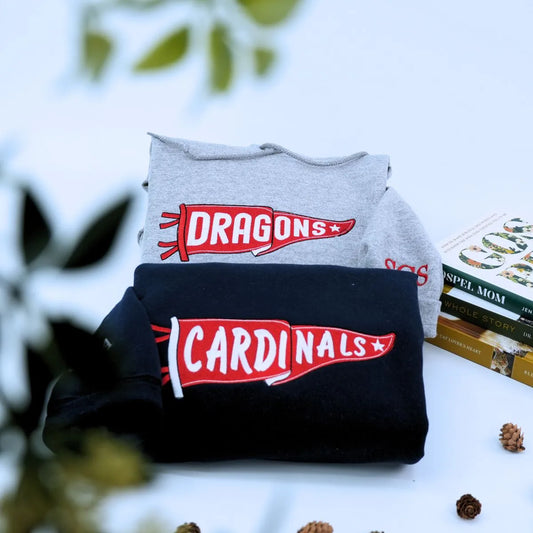 Custom embroidered sport gray and black pennant hoodies folded on table – personalized team name hoodies for school spirit, game day, and sports fans