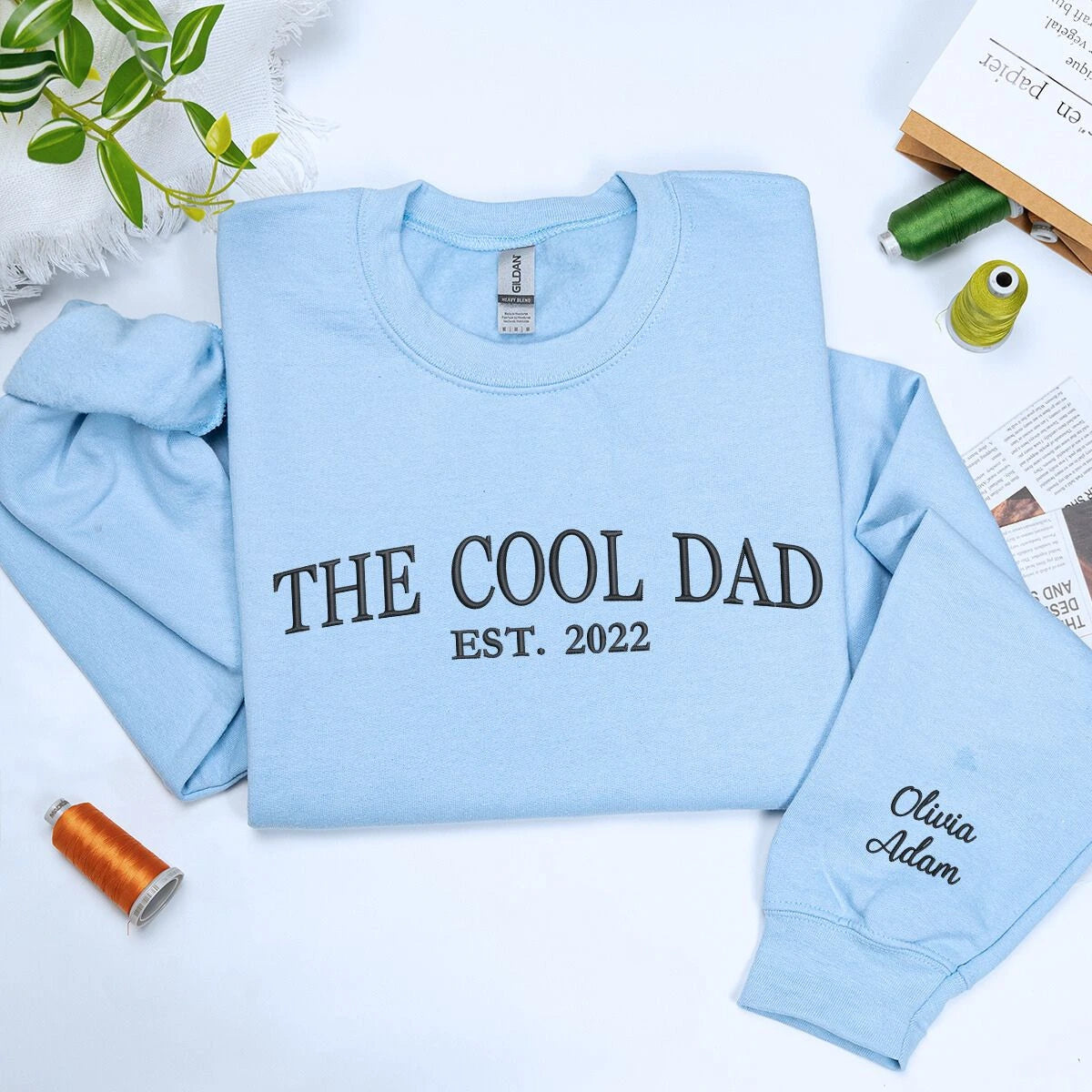 Light Blue The Cool Dad Sweatshirt with EST. 2022 embroidery and kid name on sleeve, a meaningful and cozy gift for dad