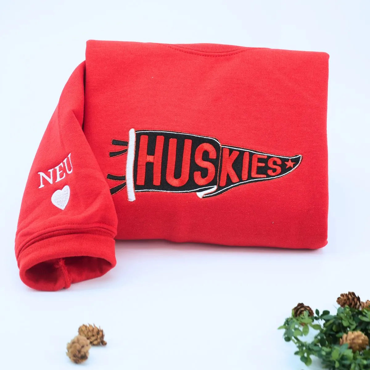 Custom embroidered red pennant sweatshirt folded on table – personalized team name sweatshirt for school spirit, game day, and sports fans