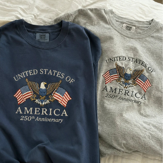 Three shirts with 'United States of America 250th Anniversary' design on a bed.