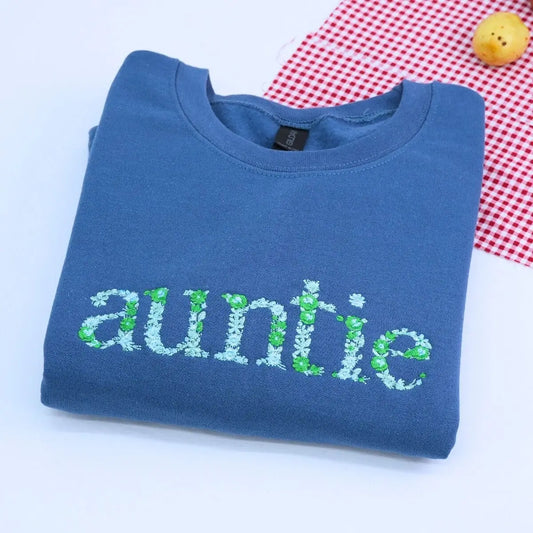Personalized auntie sweatshirt with floral embroidery and names of nieces/nephews on sleeve, custom heartfelt gift for aunt.