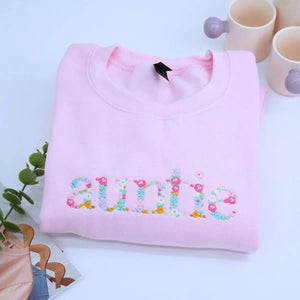 Personalized auntie sweatshirt with floral embroidery and names of nieces/nephews on sleeve, custom heartfelt gift for aunt.