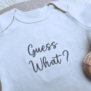 Embroidered “Guess What” baby onesie for pregnancy announcement, soft and cozy newborn bodysuit