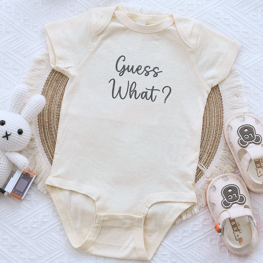 Embroidered “Guess What” baby onesie for pregnancy announcement, soft and cozy newborn bodysuit
