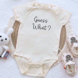 Embroidered “Guess What” baby onesie for pregnancy announcement, soft and cozy newborn bodysuit