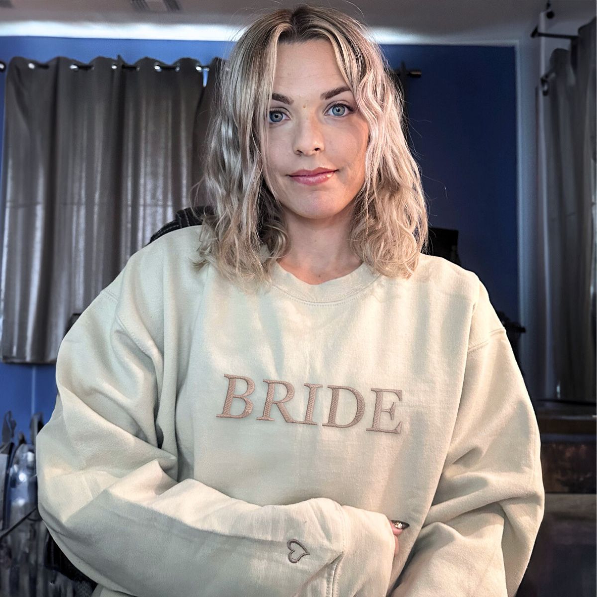 Bride wearing an oversized beige sweatshirt with embroidered lettering, cozy and stylish.