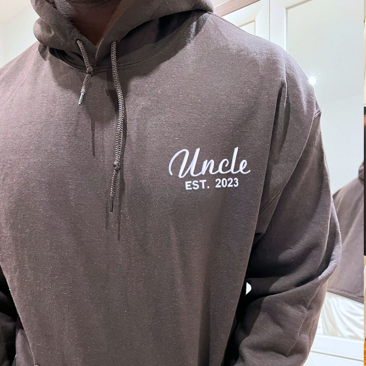 Close-up of a brown 'Uncle Est. 2023' embroidered hoodie, soft and warm fabric.