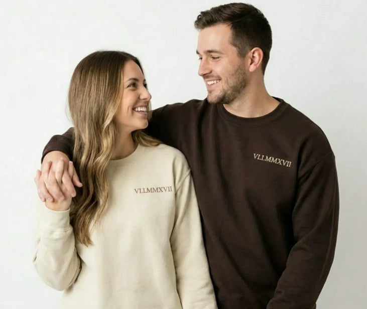 Couple wearing matching custom embroidered hoodies with Roman numeral date