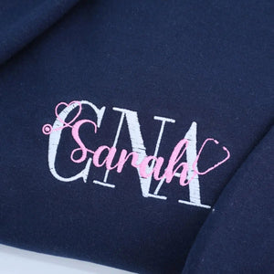 Custom embroidered CNA sweatshirt folded with title visible – perfect nursing graduation gift