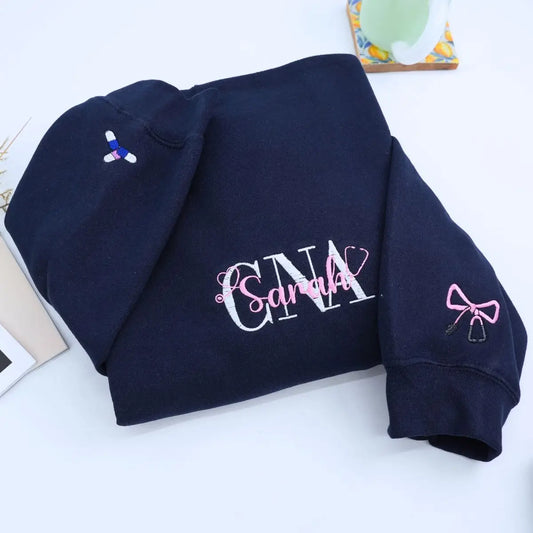 Custom embroidered CNA sweatshirt folded with title visible – perfect nursing graduation gift