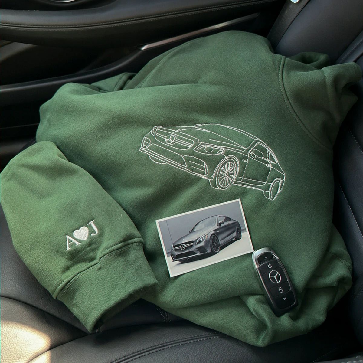 Green hoodie embroidered with car line art, cuff initials "A♡J", paired with a real photo of the car and its key fob