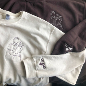 Cream and brown sweatshirts with hand-drawn couple portrait embroidery and "Te Amo" heart detail on the cuff