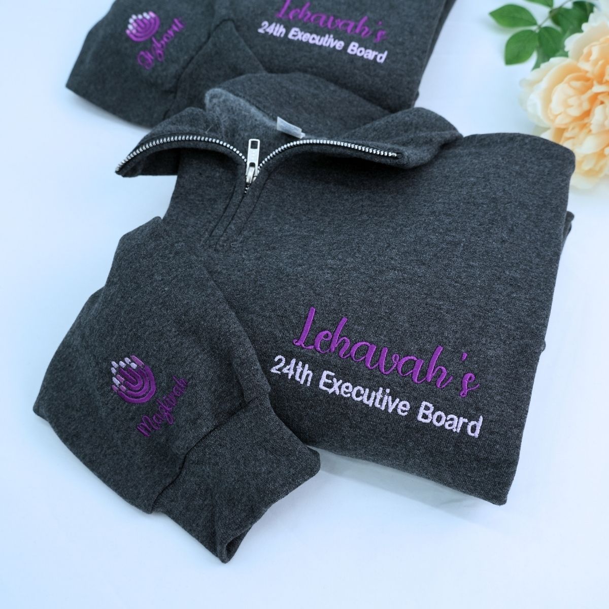 Custom embroidered quarter zip sweatshirt with company logo and text on sleeve, ideal for corporate team apparel.