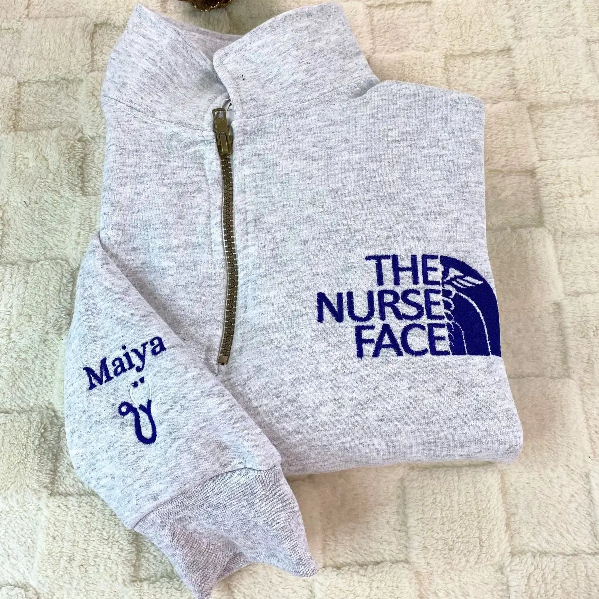 Custom embroidered quarter zip sweatshirt with nurse face design and personalized sleeve text"
