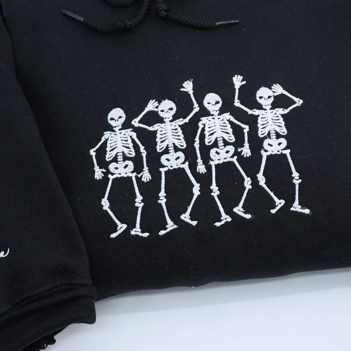 Embroidered hoodie with dancing skeletons design on black cotton fabric, unisex fit
