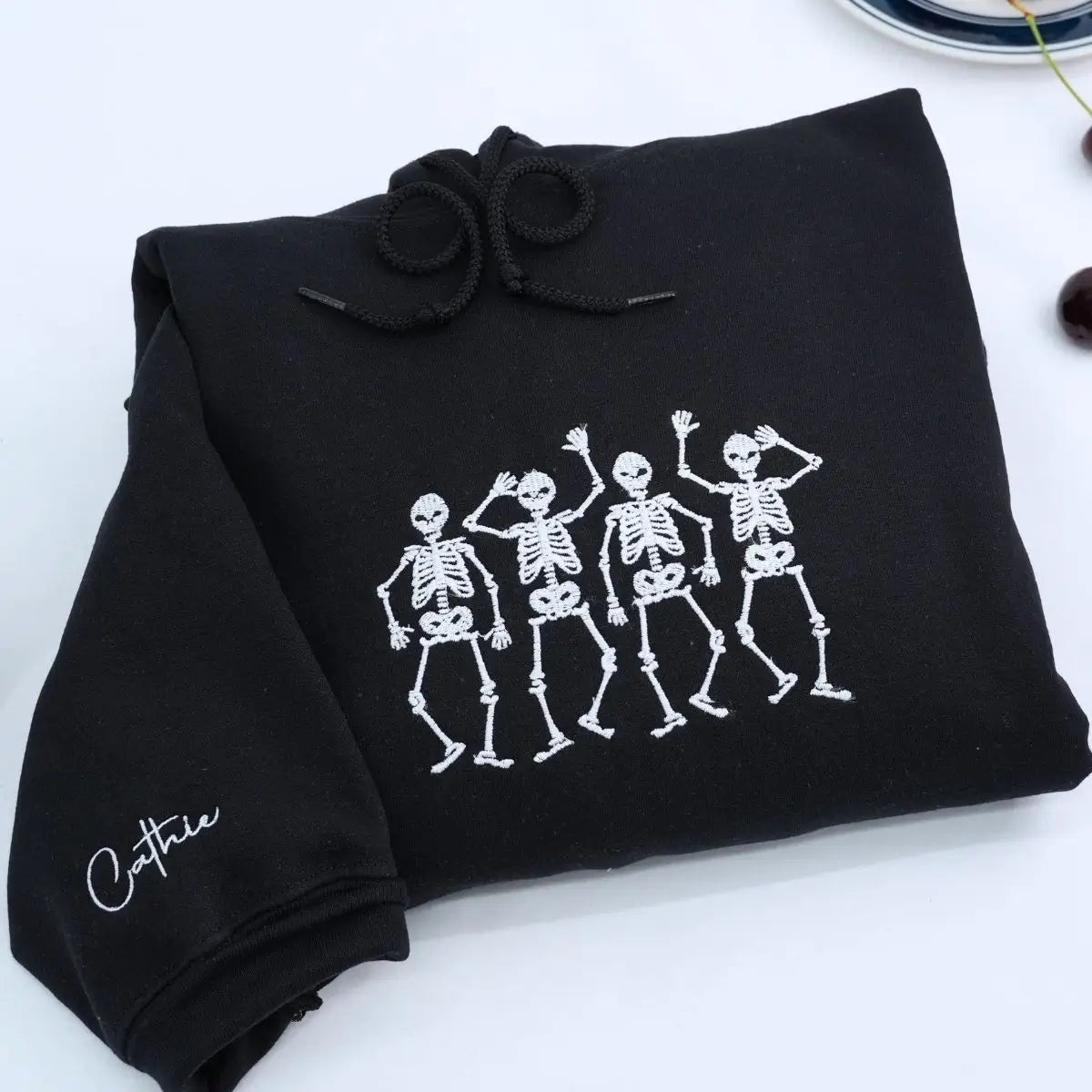 Embroidered hoodie with dancing skeletons design on black cotton fabric, unisex fit
