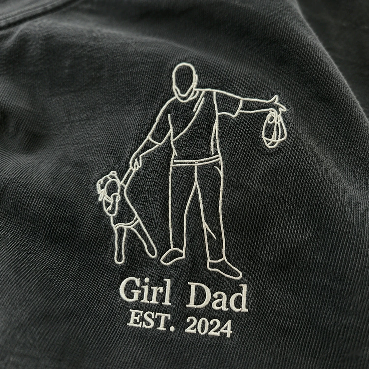 Black shirt with white embroidered design of a man and child, and text 'Girl Dad EST. 2024'.