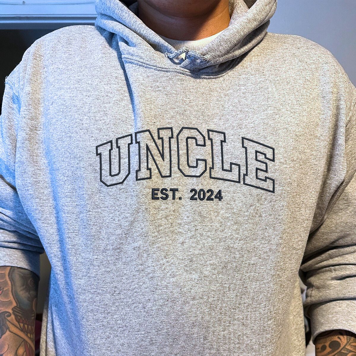 Close-up of a gray 'Uncle Est. 2024' hoodie, high-quality embroidery for a unique look.