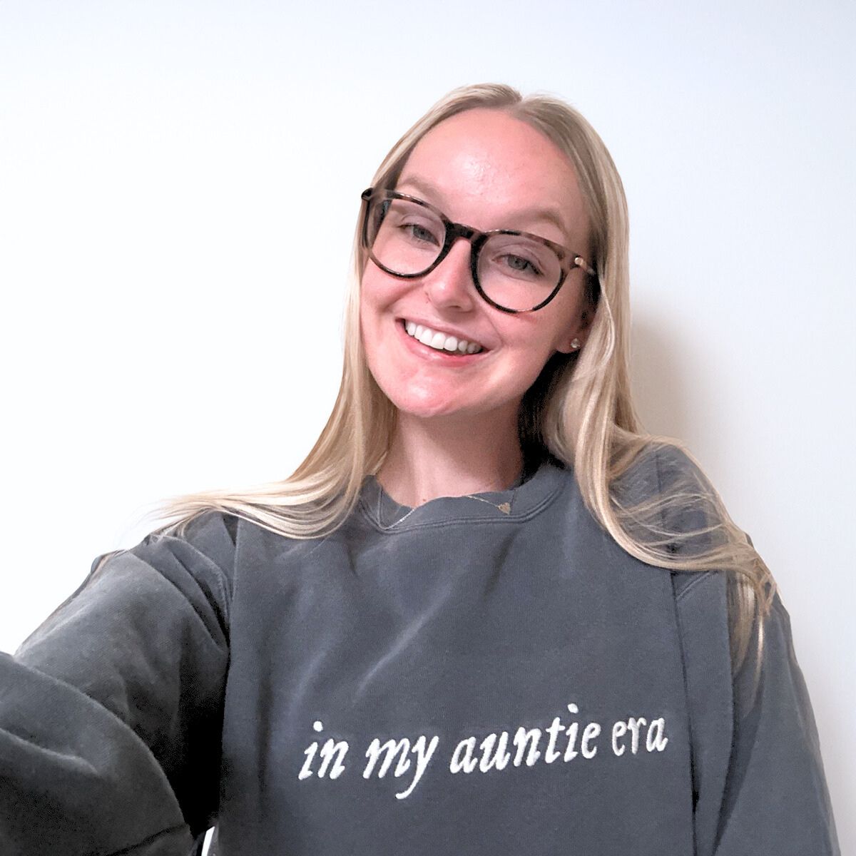 Woman with blonde hair and glasses wearing a dark gray 