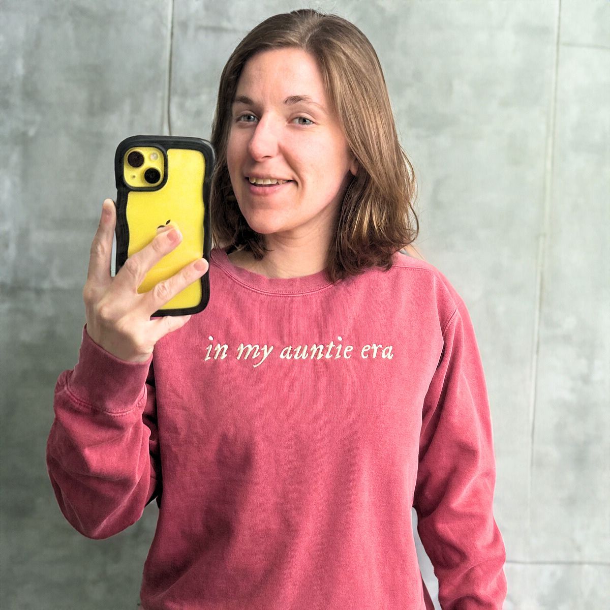 Woman with short brown hair taking a mirror selfie in a vintage red 