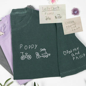Green t-shirt with embroidered text and designs on a white background
