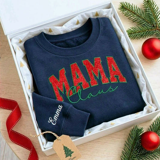 Navy Mama Claus sweatshirt with red glitter embroidery and personalized Emma sleeve, displayed in a gift box.