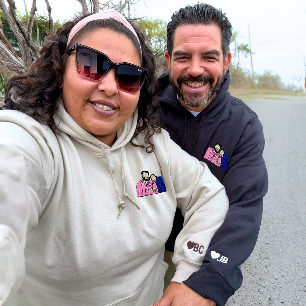 Laughing couple wearing matching black and beige Embroly hoodies with custom embroidered initials, enjoying their day.