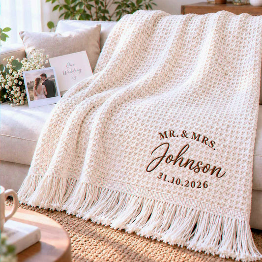 Cream waffle blanket with brown Mr. & Mrs. Johnson embroidery and personalized wedding date, draped over a sofa.