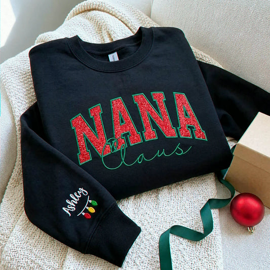 Black Nana Claus Christmas sweatshirt with red glitter lettering, green embroidered outlines and script, and personalized Ashley sleeve embroidery with colorful Christmas lights.
