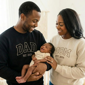 Happy parents holding newborn baby in faith-based outfit”