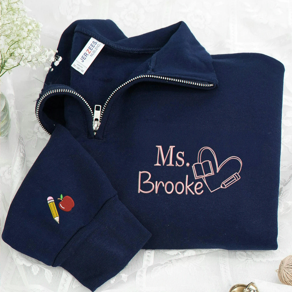 Navy teacher quarter-zip with personalized name, book-and-pencil heart on the chest and apple and pencil sleeve embroidery