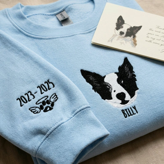 Light blue crewneck with black-and-white dog portrait, name and memorial dates embroidered on chest and sleeve