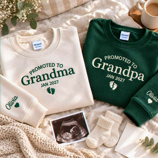 Sand and forest green Promoted to Grandma and Grandpa embroidered sweatshirts beside an ultrasound photo, a pregnancy announcement gift for grandparents-to-be.