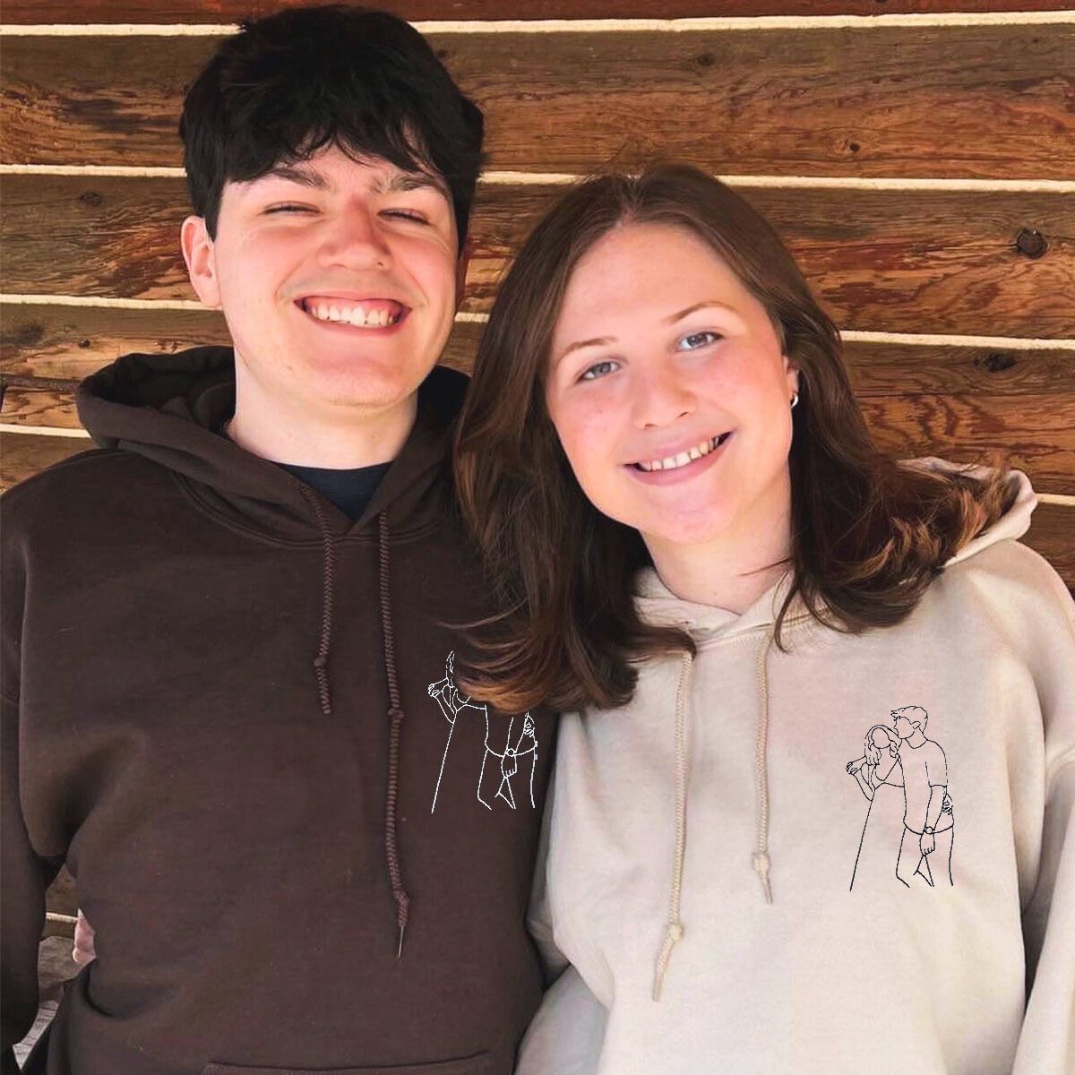 Smiling couple posing in brown and beige Embroly hoodies, featuring minimalist custom embroidery.