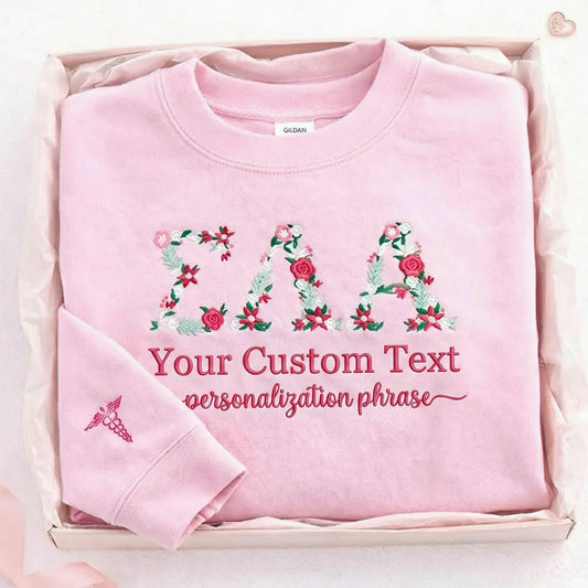 A personalized sorority light pink sweatshirt with floral embroidered letters and custom text, made for senior year, sisterhood gifts, graduation, and alumni memories.