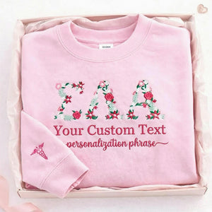 A personalized sorority light pink sweatshirt with floral embroidered letters and custom text, made for senior year, sisterhood gifts, graduation, and alumni memories.