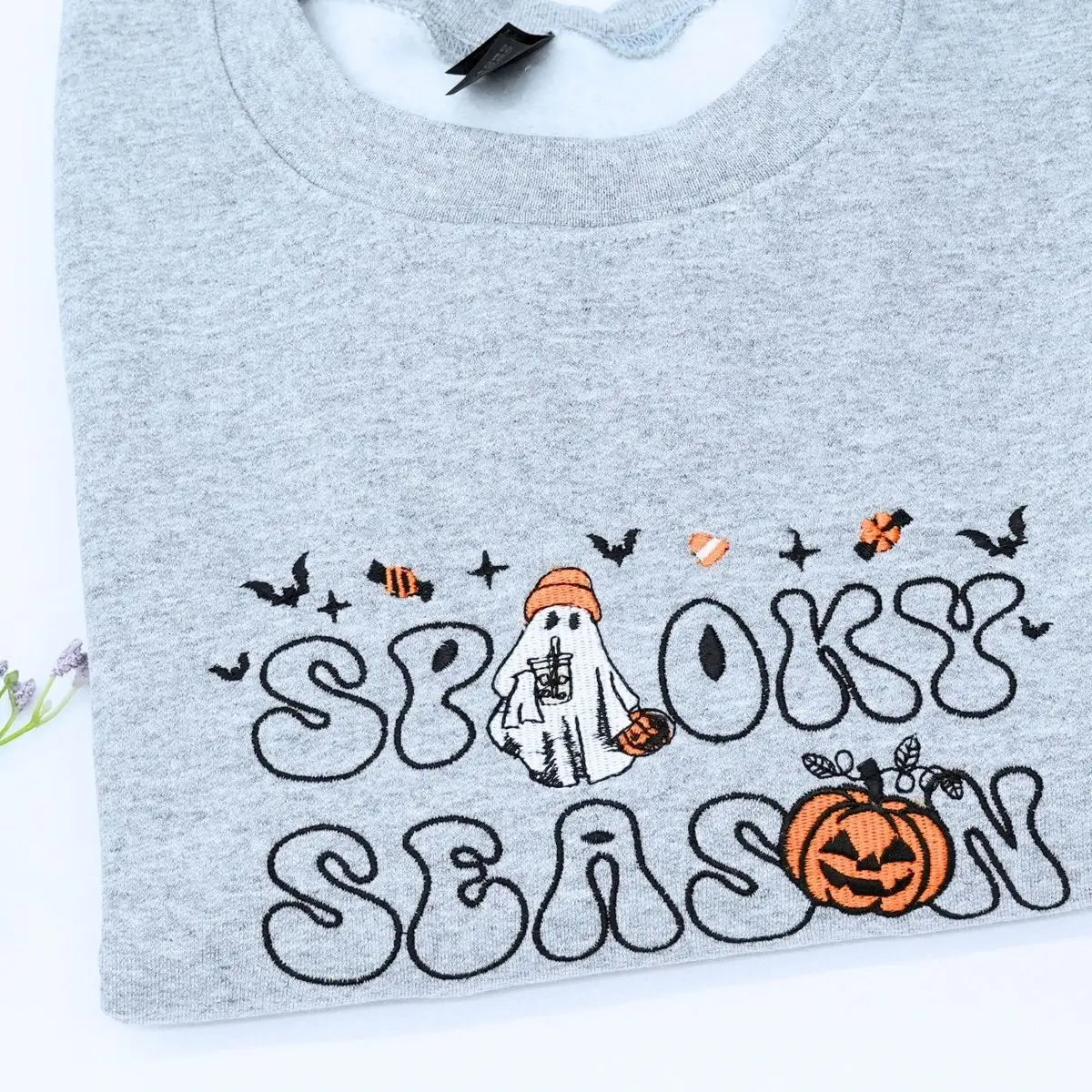 Custom embroidered spooky season sweatshirt with ghost, pumpkin and bat icons on sleeve