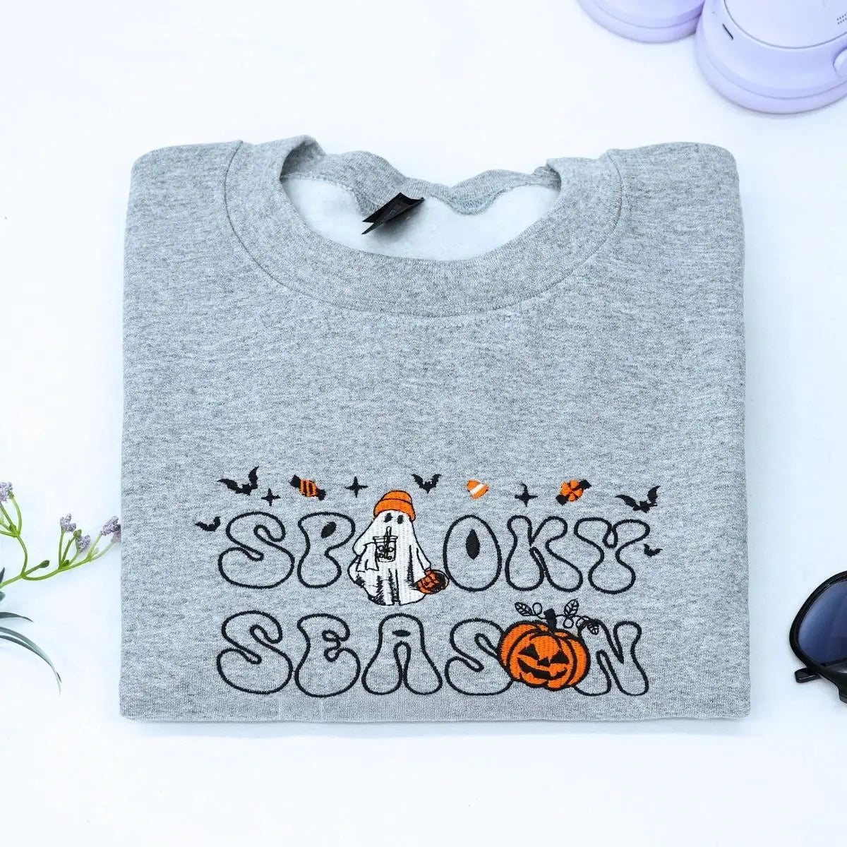 Custom embroidered spooky season sweatshirt with ghost, pumpkin and bat icons on sleeve